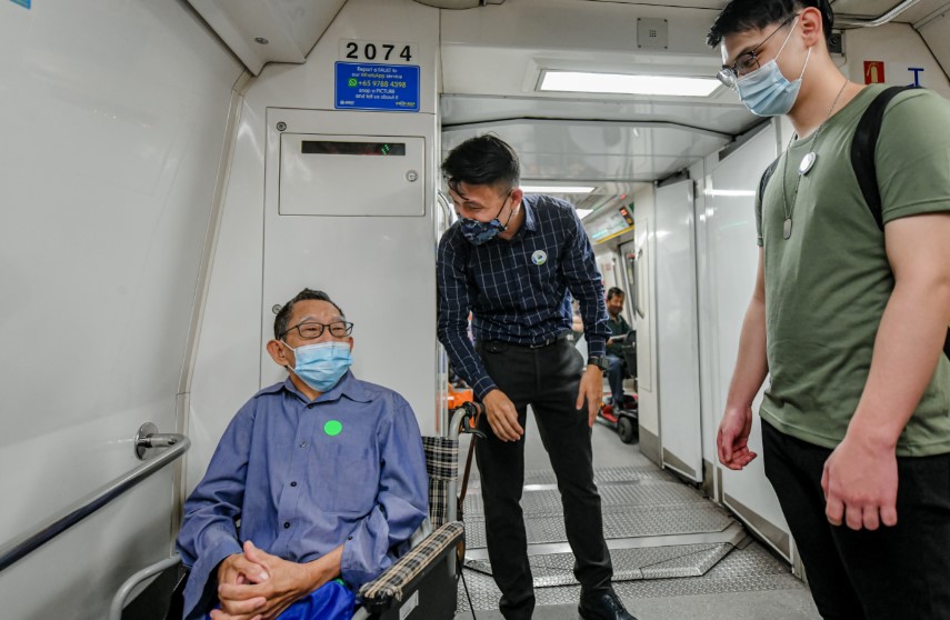 SPS Baey and a Caring Commuter Champion helping a commuter with disability on the MRT