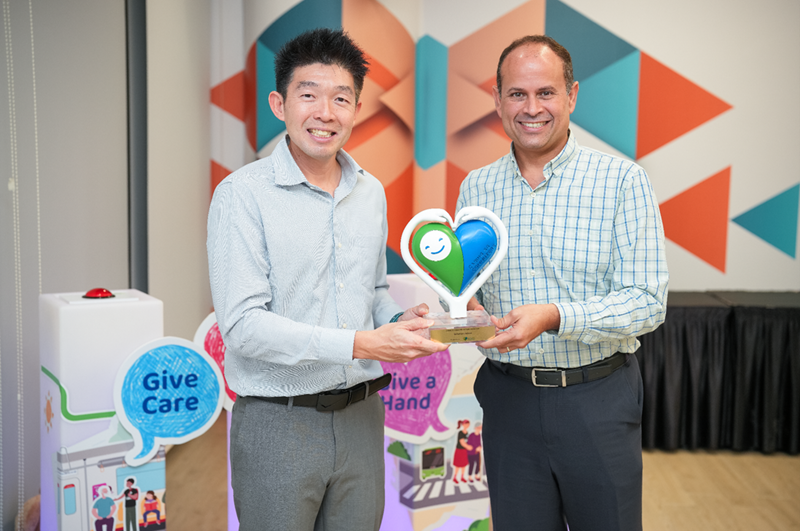 Group photo of Principal Mr Mark Minjoot (R) and HOD CCE, Mr Adrian Lim (L) with the award trophy at the Caring Commuter Week 2025