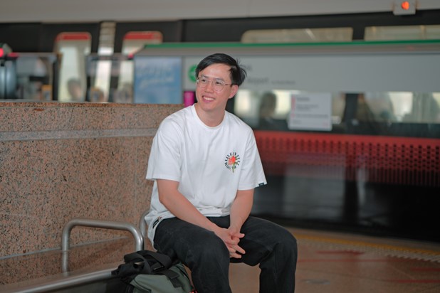 Javier sitting down on bench at Tampines MRT Station platform.)
