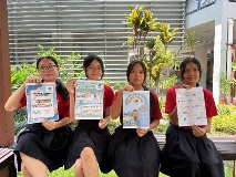 A group photo of 4 Zhenghua Secondary School students posing with e-posters designed by them.